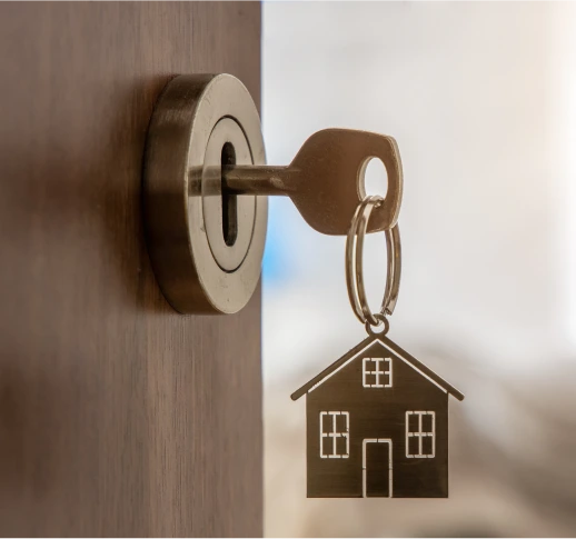 Unlocking Citizenship by Residency Through Investment A key with a house-shaped keychain in the lock of a slightly open wooden door.